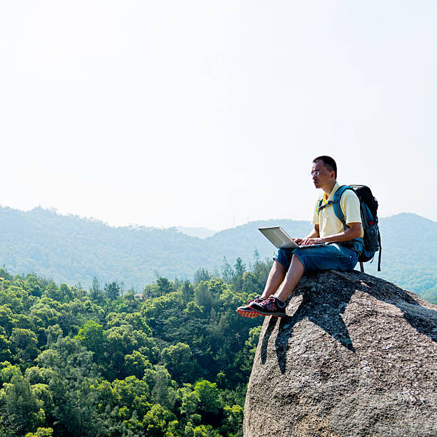 istock Asian male hiker using laptop on rock 486977770