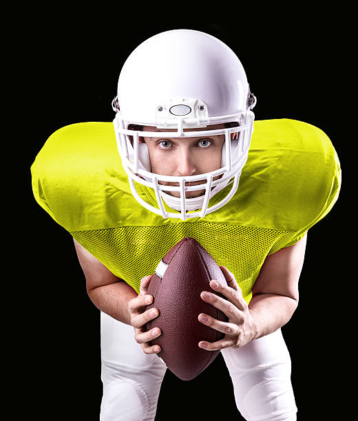 football-spieler auf gelben uniform isoliert auf schwarzem hintergrund - football helmet american football yellow american football uniform stock-fotos und bilder