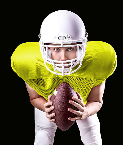 istock Football Player on yellow uniform isolated on black background 486977924