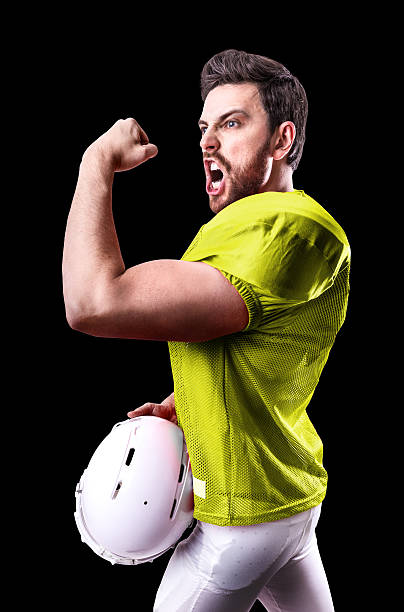 football-spieler auf gelben uniform isoliert auf schwarzem hintergrund - football helmet american football yellow american football uniform stock-fotos und bilder