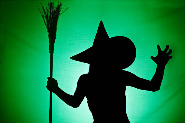 Witch Silhouette A green and black silhouette of a wicked witch holding her broom. wicked witch stock pictures, royalty-free photos & images