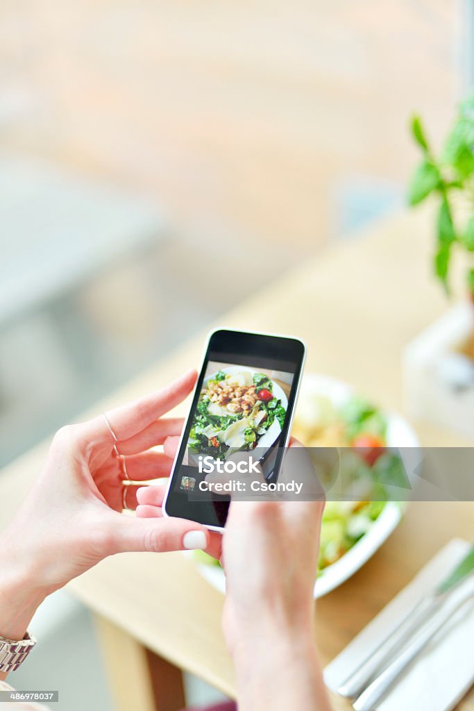 Smartphone taking picture from salad Young woman making picture from her food with smartphone. Auto Post Production Filter Stock Photo