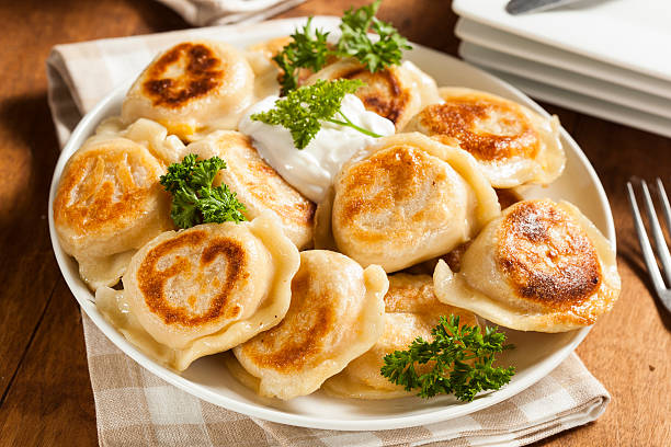 Homemade Polish Pierogis with Sour Cream Homemade Polish Pierogis with Sour Cream and Parsley polish culture photos stock pictures, royalty-free photos & images