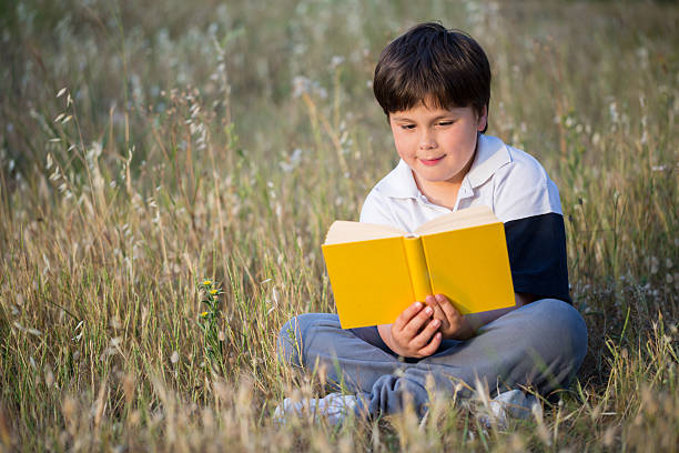 istock little boy reading book in the meadow 486978674