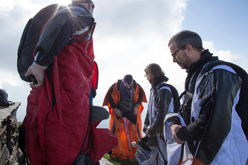 Group of wingsuit jumpers get ready to launch, mountain summit