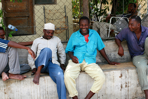 Zanzibar, Tanzania - February 20, 2008: A group of several Tanzanian men resting, sitting in the shade of the house.