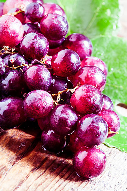 istock Round purple grapes with leaves on the old wooden table 486987536