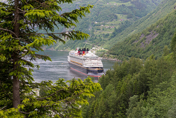 Geiranger, Norway - June 24, 2015: View of a cruise ship at Geiranger Fjord in Sunnmare region of More og Romsdal county, framed by nature and anchored by the small tourist village in Geiranger, Norway