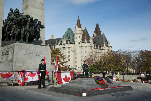 Ottawa, Canada - October 27, 2014: Ceremonial guards stand at attention while mourners pay respect at the Ottawa Cenotaph where guard Nathan Cirillo was shot 5 days before.