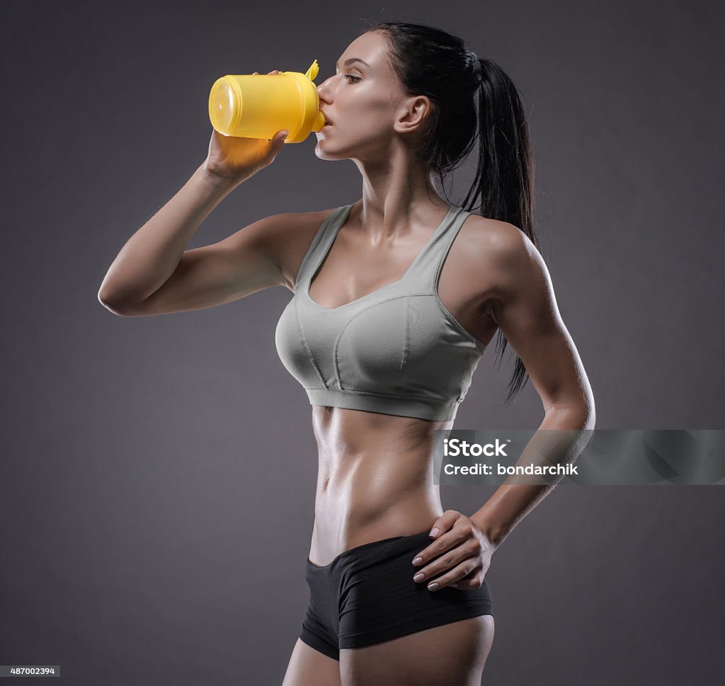 athletic young woman doing a fitness workout Fitness girl with shaker on a dark background 2015 Stock Photo