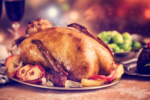 Traditional British holiday goose dinner with apples, brussels sprouts and Christmas Pudding