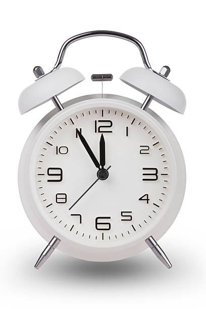 istock White alarm clock with hands at 5 minutes till 12 487018132