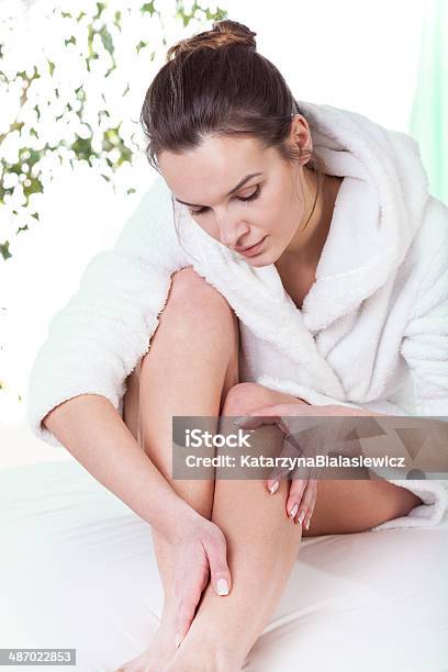 Woman Rubbing Her Leg Stock Photo - Download Image Now - Bathrobe, Crude Oil, Essential Oil