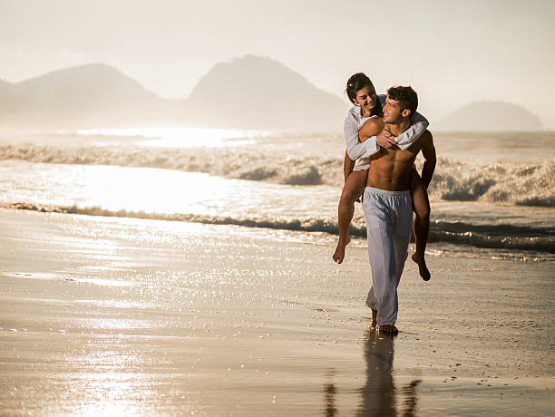 istock Loving couple piggybacking on the beach at sunset. 487025186