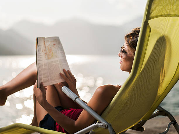 Smiling woman reading a magazine in deck chair.