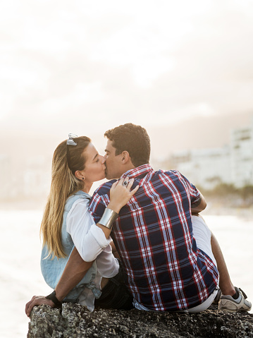 Romantic couple kissing on the rock near the beach.