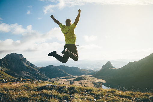 Freedom. Man jumping in the air with mountain landscape on background.