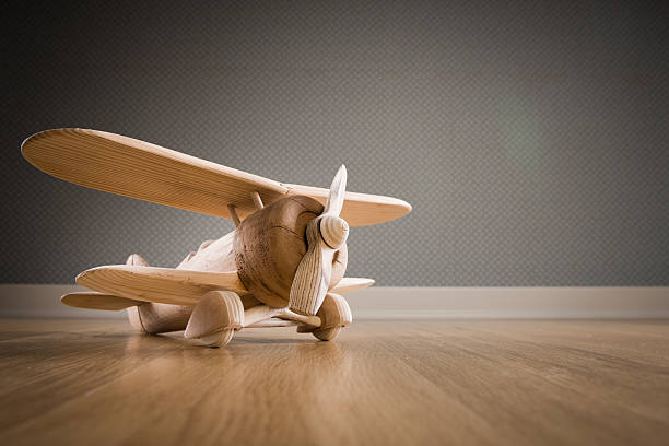 Wooden toy plane hand carved model on hardwood floor.
