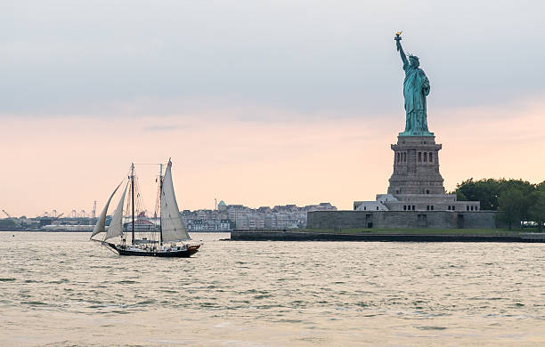 New York Statue of Liberty with Sailboat at Sunset stock photo
