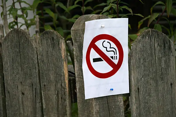 non-smoking sign on sheet of paper on wooden fence