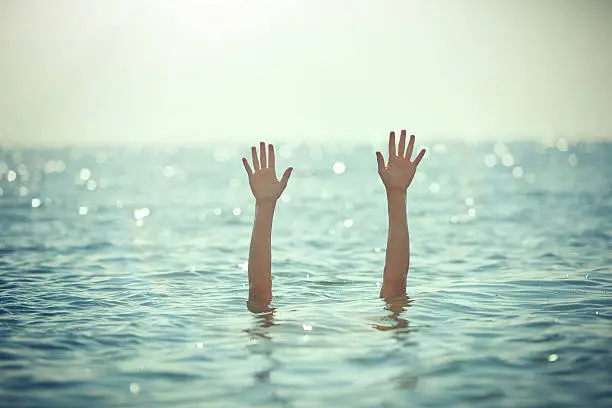 unrecognizable man hands waving for help, drowning into the sea.sunlight.horizontal shot.