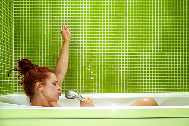 great music in bathtub side view of woman in bathtub singing, enjoying bath and having fun.photo taken inside bathroom, green tile on the wall. body care shower stock pictures, royalty-free photos & images