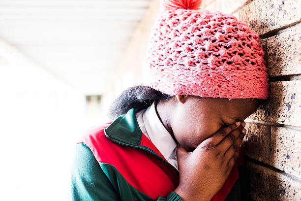 A portrait of a school girl hiding her face in despair, she is a victim of school violence.