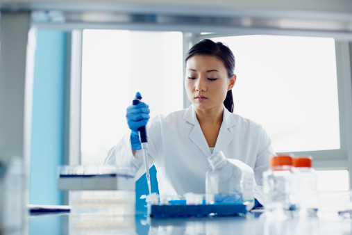Female scientist using pipette in modern research laboratory