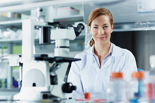 portrait of smiling female scientist - microscope laboratory scientist women photos et images de collection