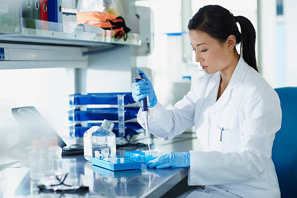 scientist pipetting samples into eppendorf tubes - deney fotoğraflar stok fotoğraflar ve resimler