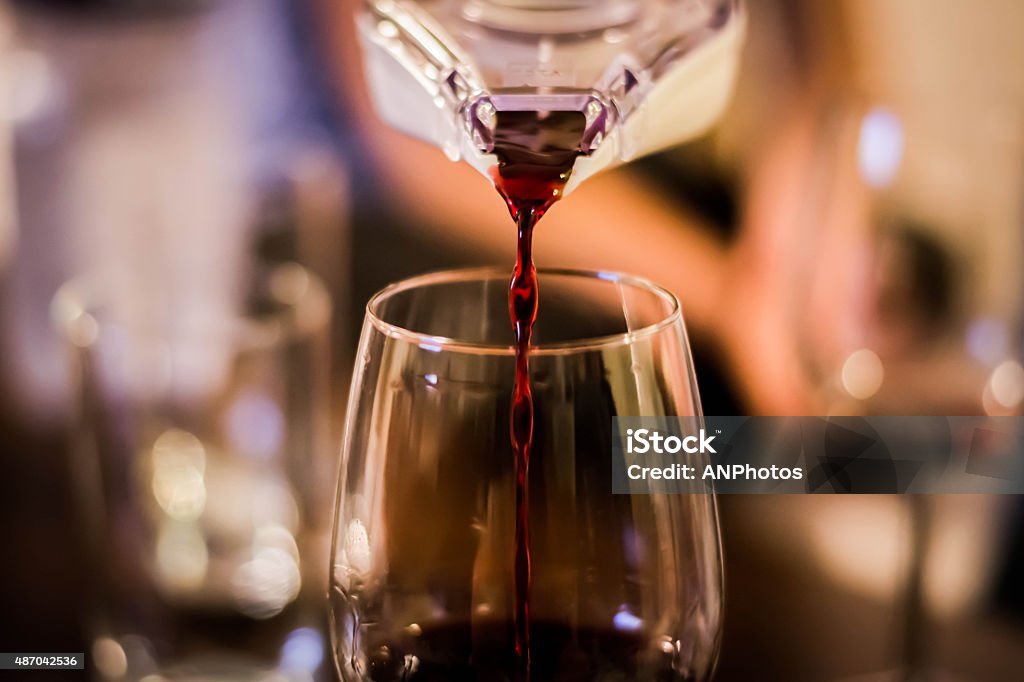 Pouring Red Red Wine Red Wine is being poured into glass out from a special wine bottle nozzle. 2015 Stock Photo