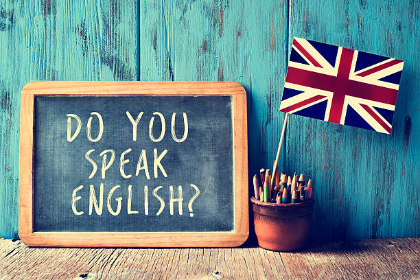 text do you speak english? in a chalkboard, filtered a chalkboard with the text do you speak english? written in it, a pot with pencils and the flag of the United Kingdom, on a wooden desk, with a filter effect cross processed stock pictures, royalty-free photos & images