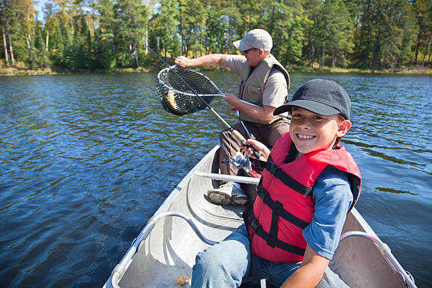 Young boy fisherman smiles at catch of nice walleye Young boy fisherman smiles while his dad takes the fish out of the net rowing boat fishing stock pictures, royalty-free photos & images