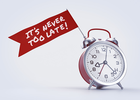 Alarm clock with a red banner and handwritten phrase on it. 3D rendered graphics on light background. The text on the banner created with the «Permanent Marker» font, distributed under Apache License Version 2.0.