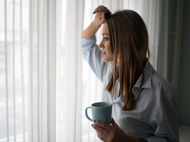 istock Young pensive woman enjoying in coffee while looking through window. 487053942