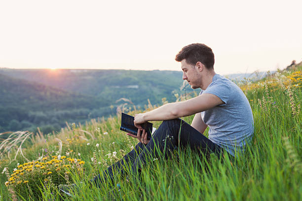 istock man sits on the hill and reading a book 487054212