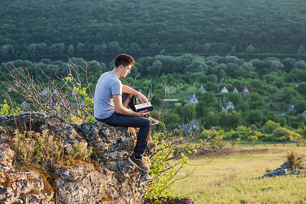 istock man sits on the edge of a cliff and reading 487054216