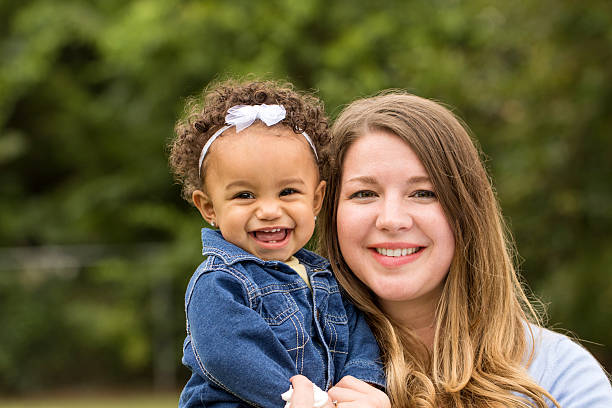 Mother and daugher Adorable little girl laughing. Mixed family.  Portrait of a Caucasian mother and bi-racial daughter. adoption photos stock pictures, royalty-free photos & images