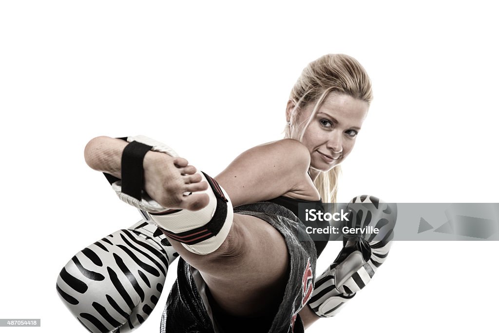 Lean Female kickboxer executing a kick ("Kickboxing" is written on her shorts). 2015 Stock Photo