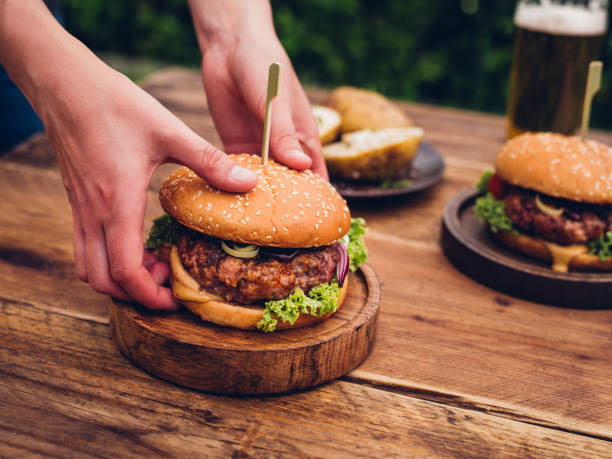 istock Person picking up gourmet cheese burger from an outdoor table 487054582