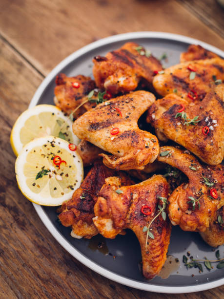 istock Hot and spicy chicken wings on plate with lemon slices 487054724