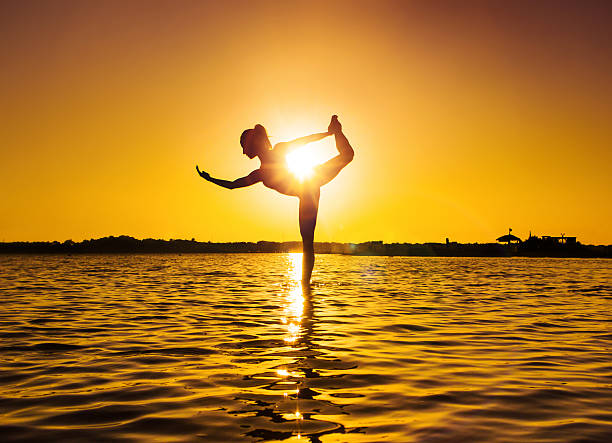 istock Young woman doing yoga at sunset beach 487054778