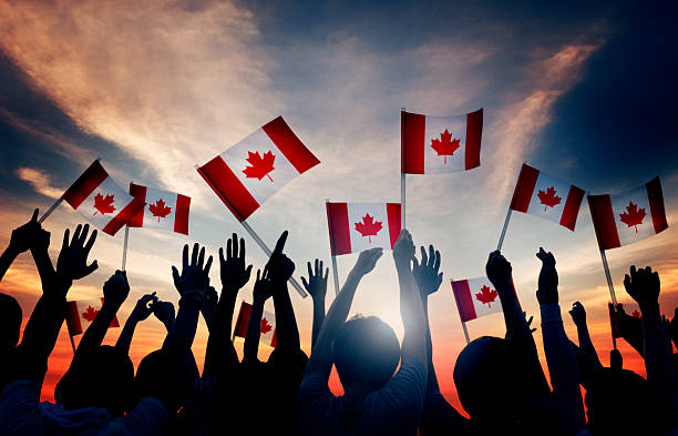 Group People Waving Canadian Flags Back Lit ***NOTE TO INSPECTOR: All models in this image have signed model releases. Some models have been duplicated more than once.*** canadian culture stock pictures, royalty-free photos & images