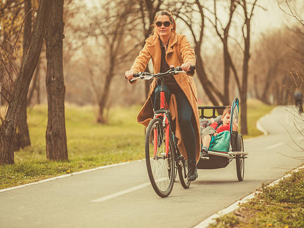 istock Mother riding a bicycle with kids on trailer 487056794