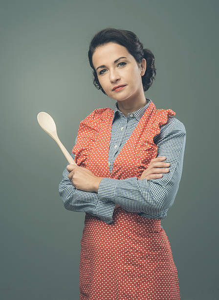Attractive old-timey housewife in apron holding a wooden spoon