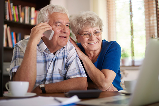 Smiling senior couple making  deal via telephone