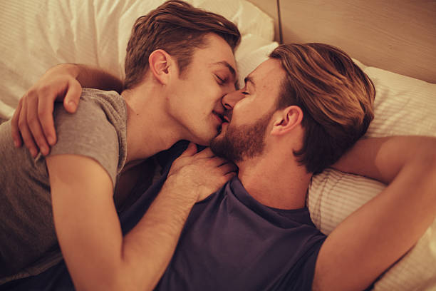 joven gay pareja en el dormitorio. - gay man homosexual men kissing fotografías e imágenes de stock