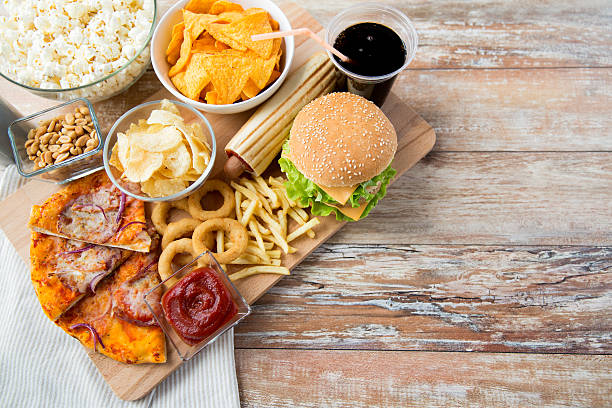 close up of fast food snacks and drink on table - frisdrank-fotos stockfoto's en -beelden