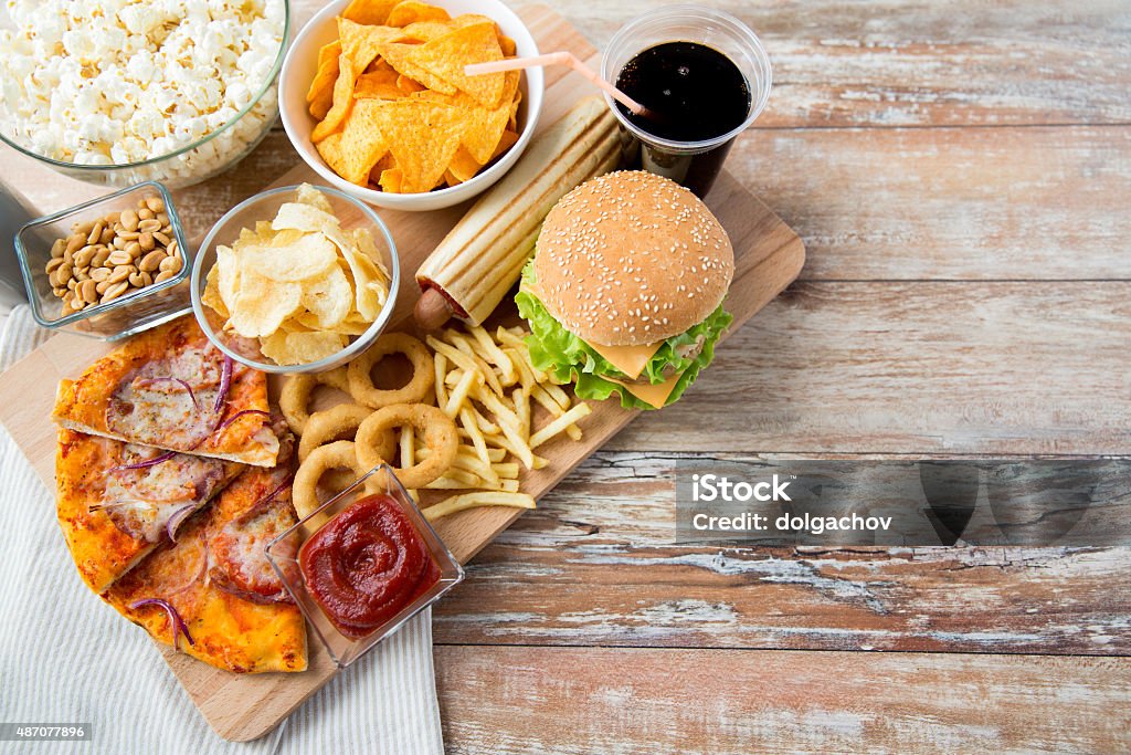 close up of fast food snacks and drink on table fast food, junk-food and unhealthy eating concept - close up of fast food snacks and coca cola drink on wooden table Fast Food Stock Photo