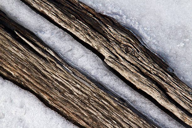 Weathered wood on a railroad tie is encased in snow and ice.